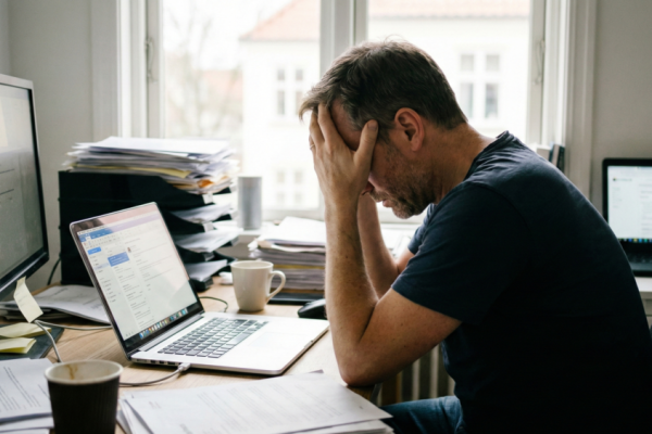Profissional em ambiente de escritório demonstrando sinais de exaustão e estresse, com foco na conscientização sobre a Síndrome de Burnout.